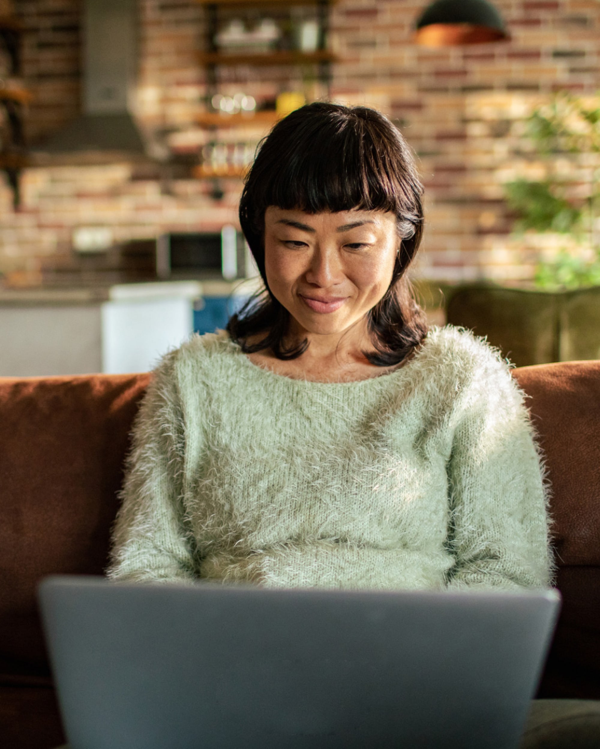 Uma mulher de suéter está usando um laptop