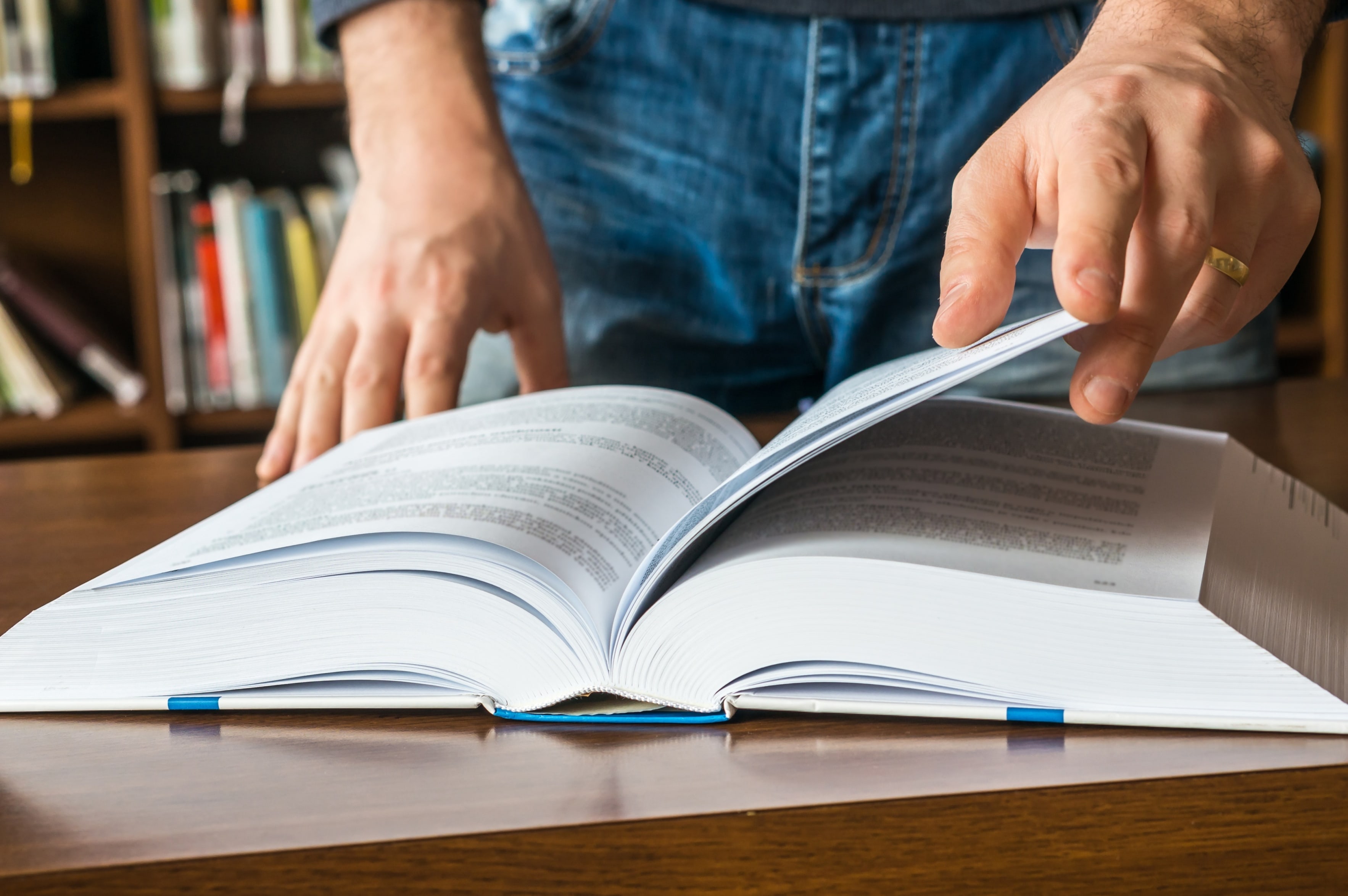 Close das mãos de uma pessoa folheando um livro