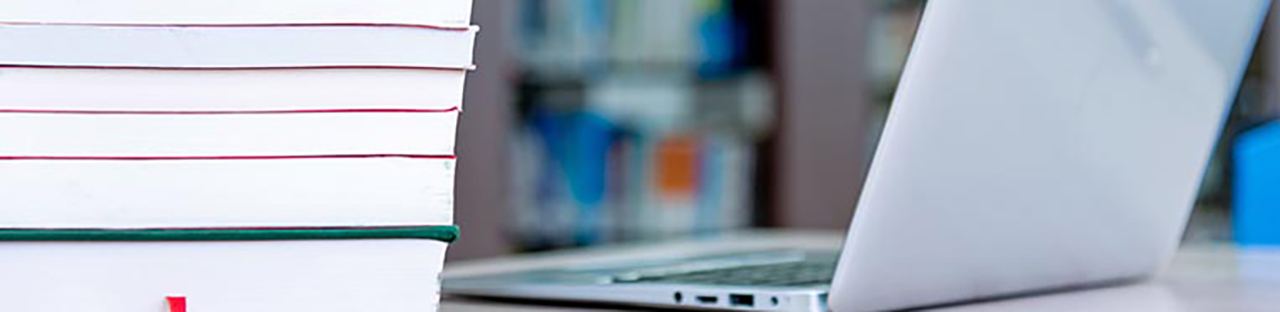 Laptop on desk with stack of books