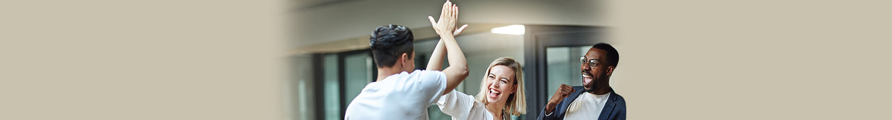 Duas pessoas comemorando com um high five enquanto uma terceira pessoa observa